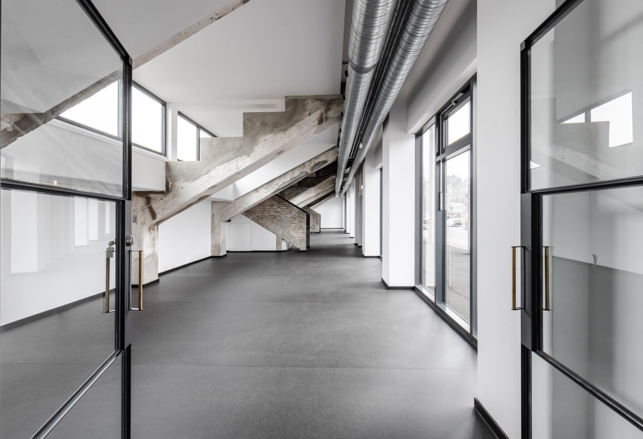 Studio Room inside AVUS Tribüne with daylight, concrete floor and visible heritage structure